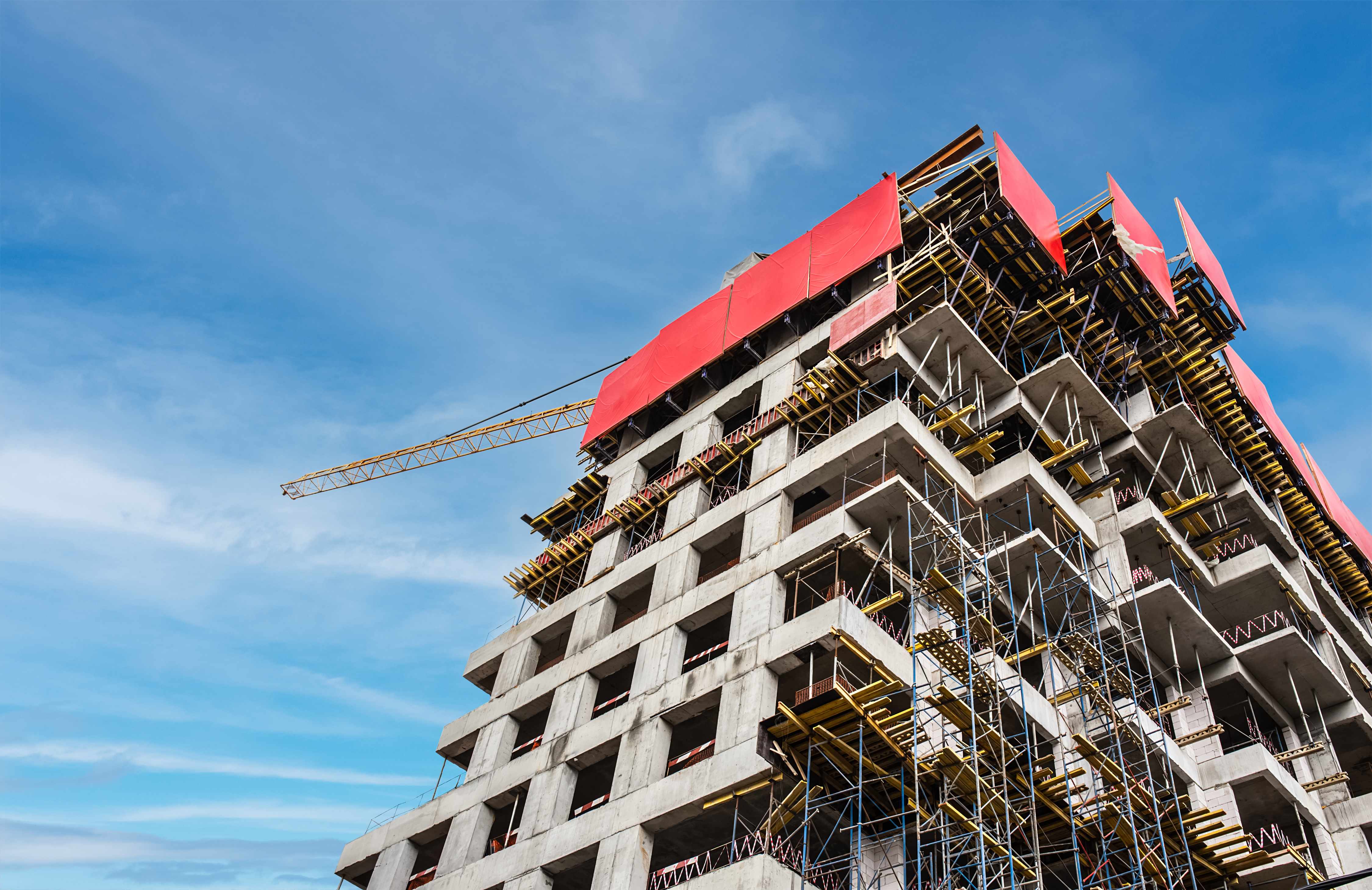 Construction site with crane and building against blue sky.